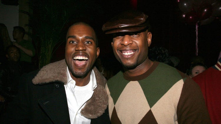 Talib Kweli wearing hat as Kanye West laughs