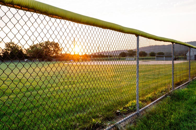 Empty baseball field, school sports field with chainlink fence at high school or public park in rural small town America.