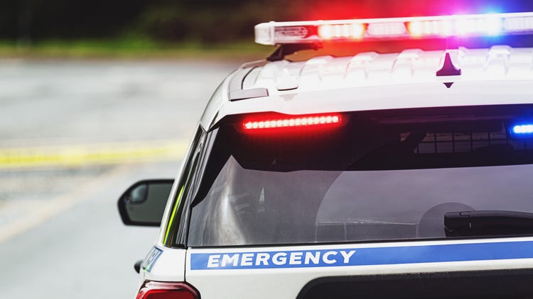 Police block a road on an emergency scene.