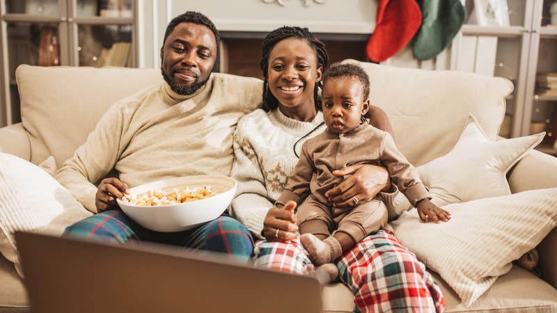 Family of three watching TV together at home for Christmas